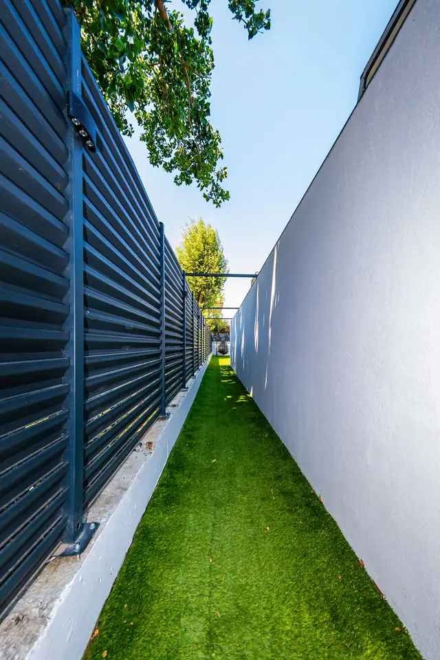 Bungalovlar arasındaki yeşil çimli dar bahçe patikası